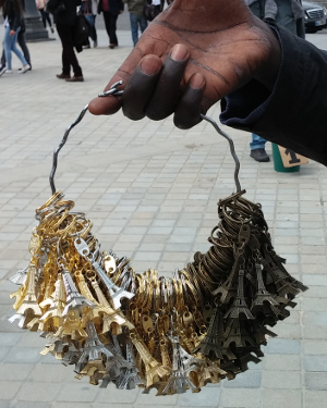 Seller holding huge wire-ring with many Eiffel-tower-key-fobs.